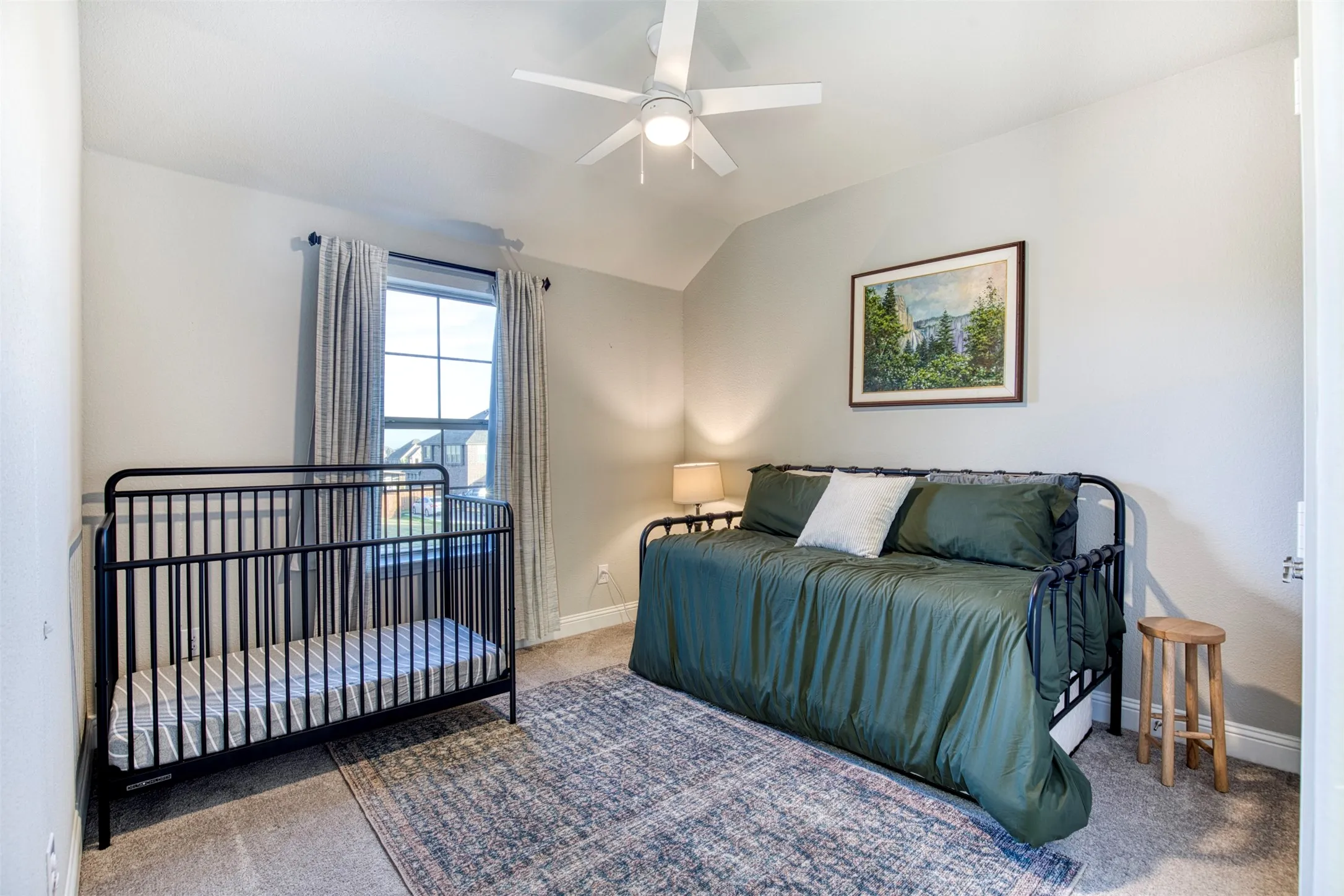 Secondary bedroom with sloped ceiling and ceiling fan.