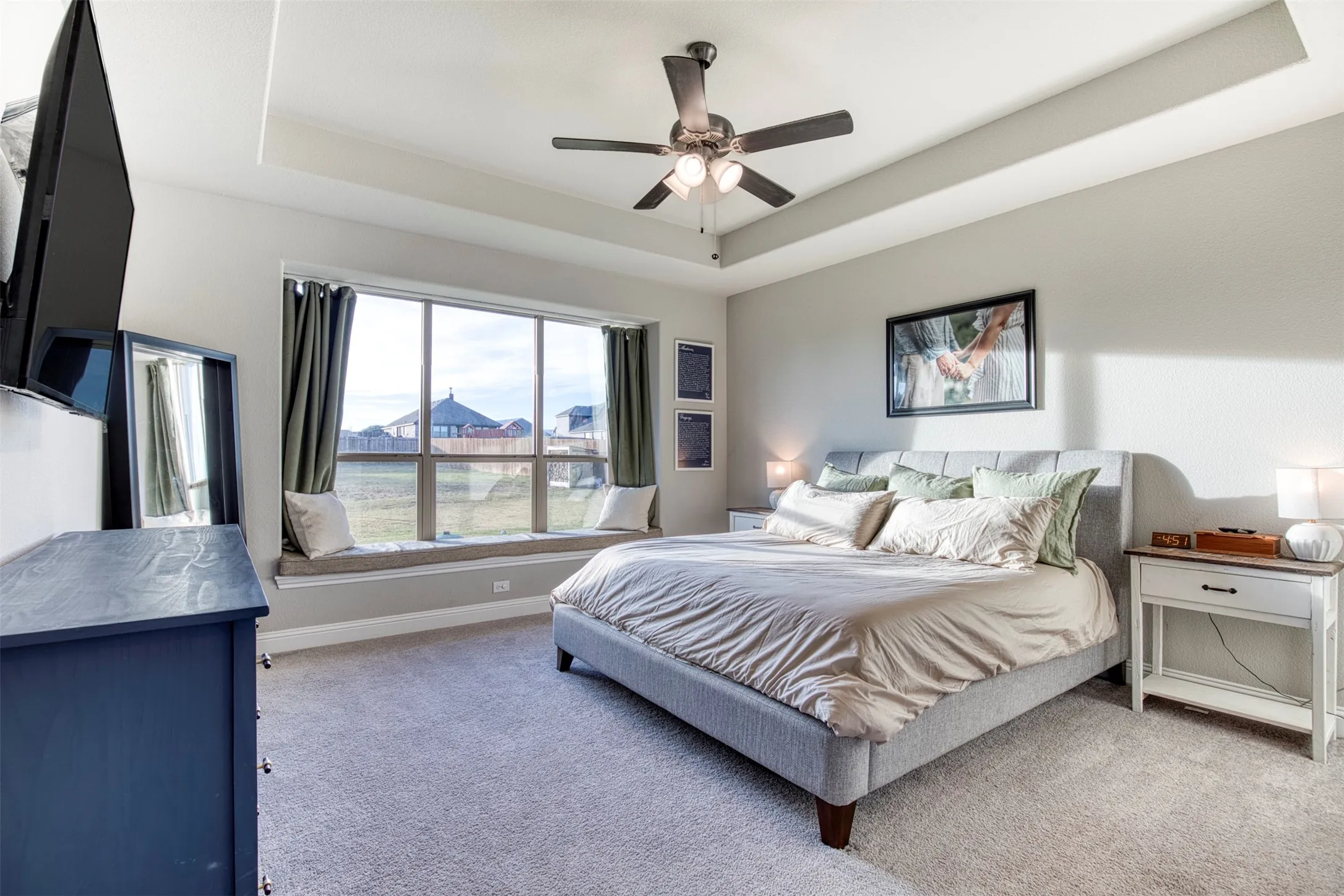 Primary suite with trey ceiling and sitting bench overlooking the scenic backyard.