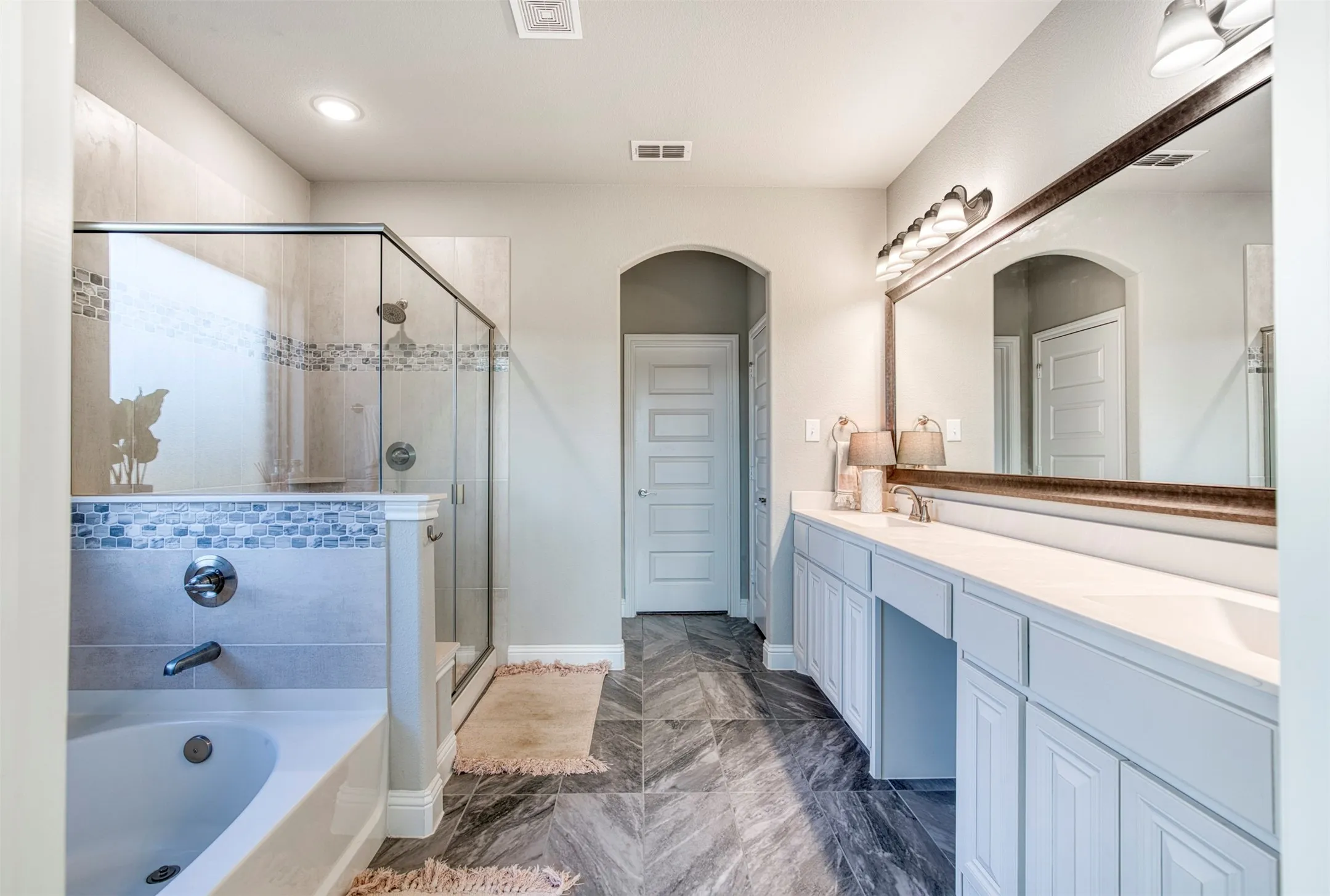Luxury, spa-like, en-suite bath with dual sinks and vanity sitting area.
