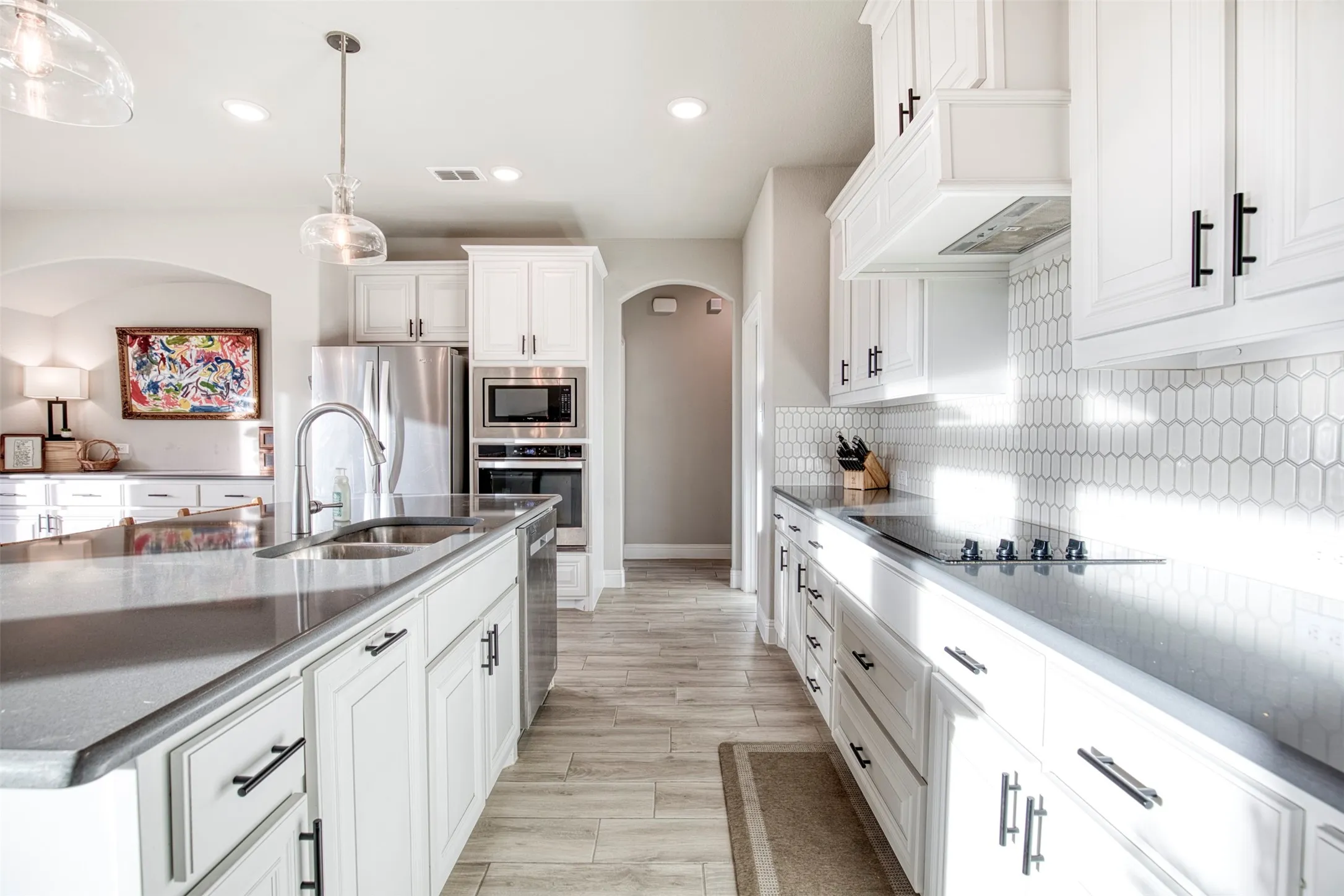 Kitchen boasts electric, glass cooktop, double stainless steel sink, and stainless steel appliances.