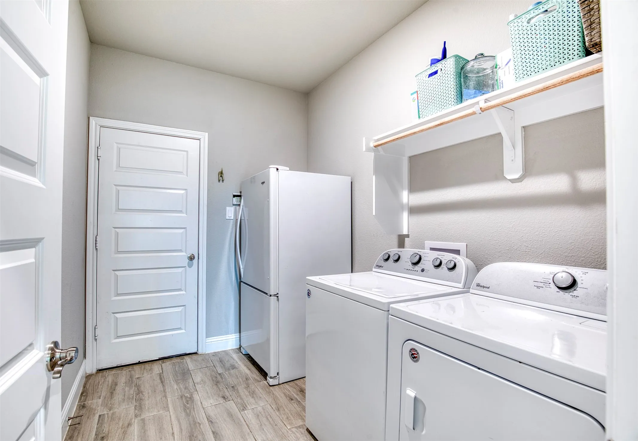 Spacious laundry room with custom shelving and room for additional fridge.