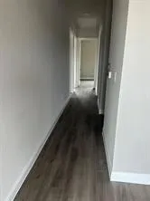 Hallway featuring baseboards and dark wood-type flooring