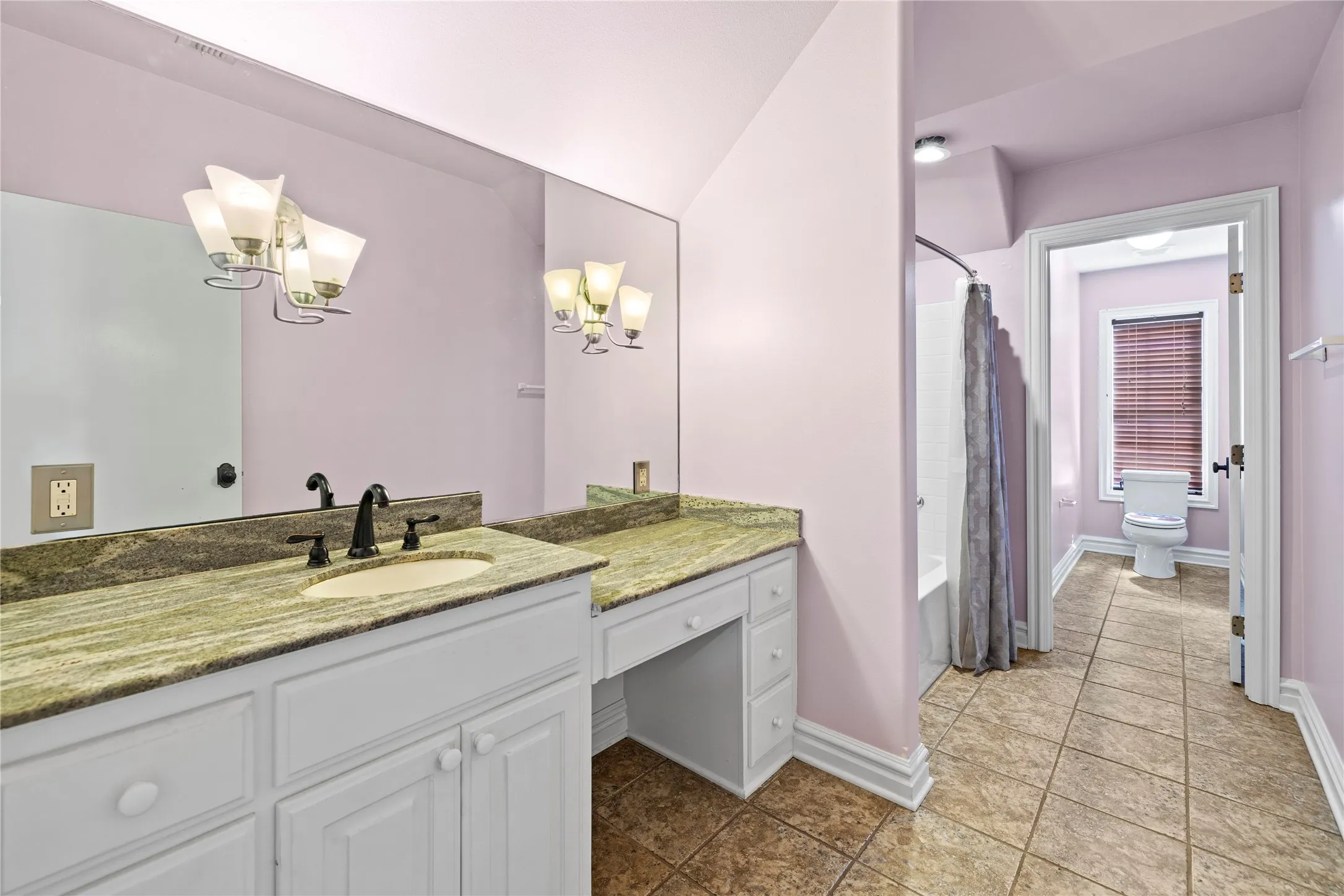 Full bath with shower / bathtub combination with curtain, vanity, a chandelier, and dark tile patterned flooring