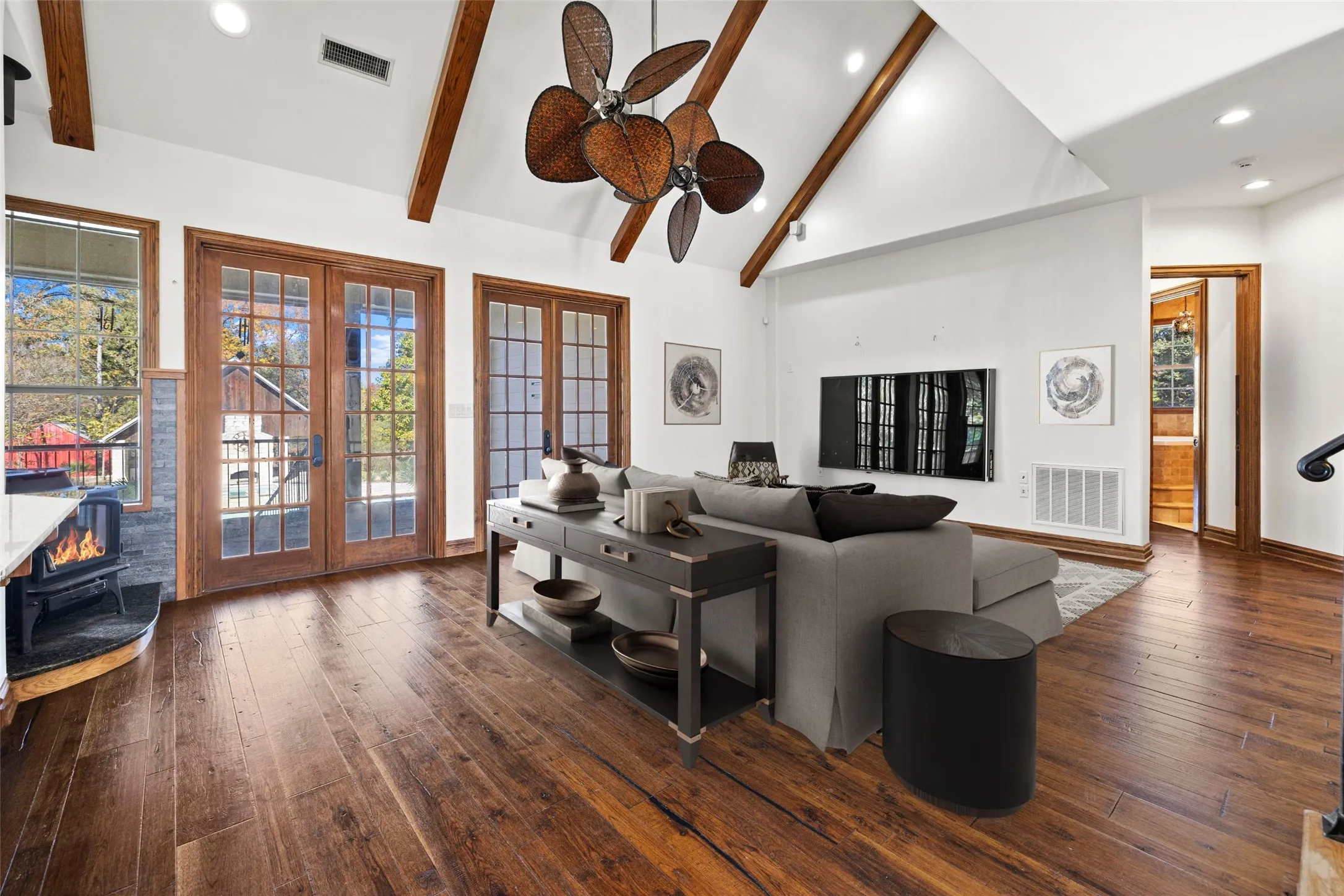 Living room featuring french doors, a wood stove, beamed ceiling, wood-type flooring, and recessed lighting
