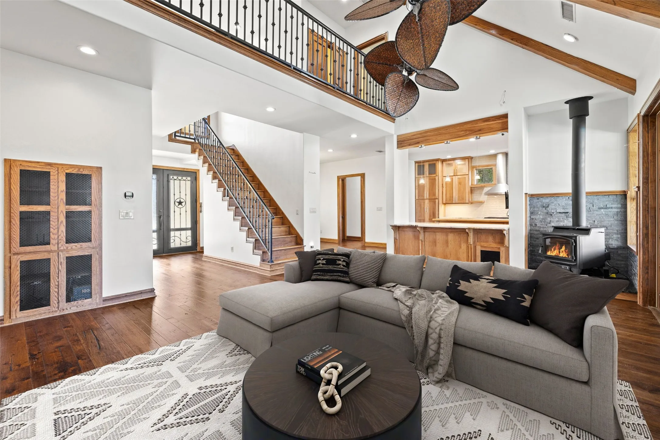 Living area featuring hardwood / wood-style flooring, stairs, a high ceiling, beam ceiling, and a wood stove