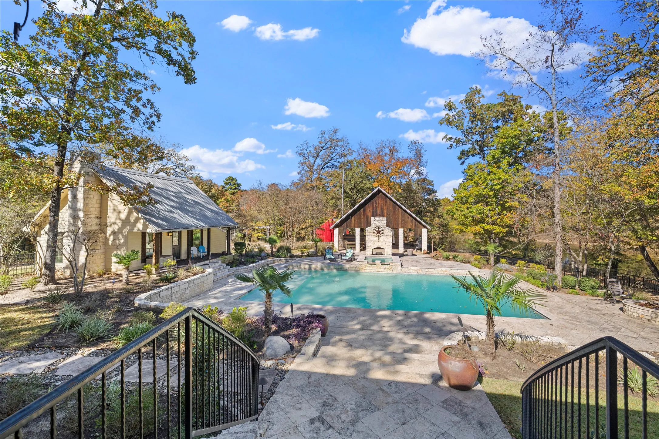 Outdoor pool featuring a patio area, an outbuilding, an exterior structure, and view of scattered trees
