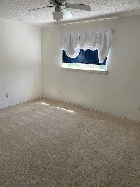 Bedroom featuring a textured ceiling, ceiling fan, and carpet flooring