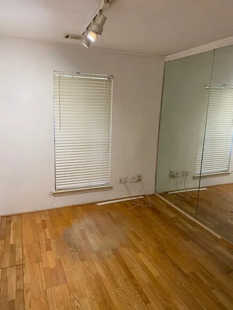 Unfurnished bedroom featuring track lighting, crown molding, and wood finished floors