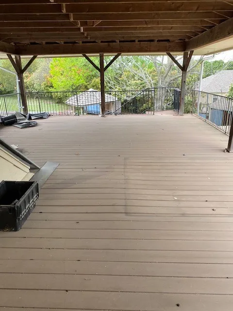 View of wooden second floor covered deck overlooking back yard.