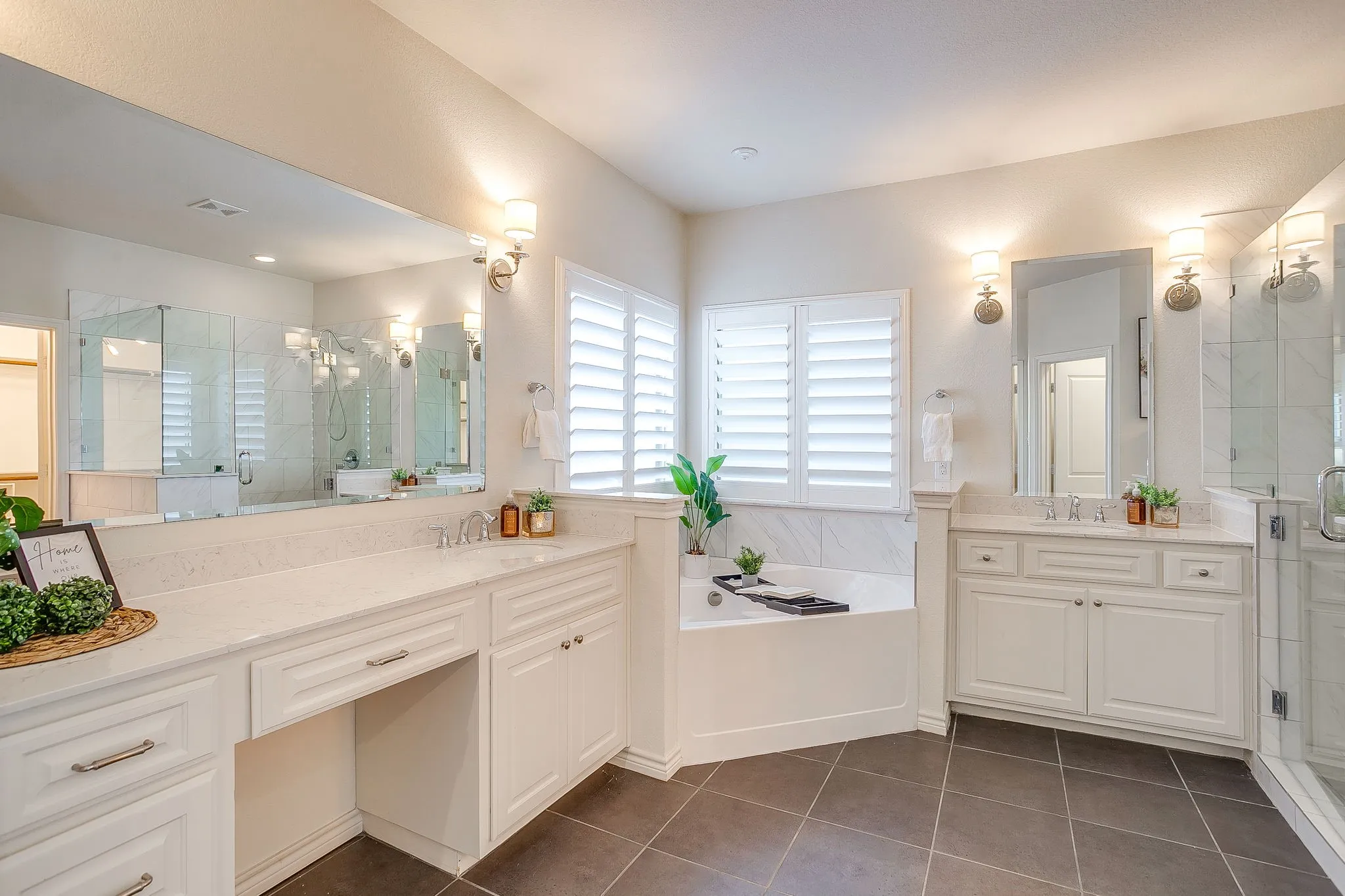 Full bath featuring a shower stall, two vanities, dark tile patterned flooring, and a garden tub