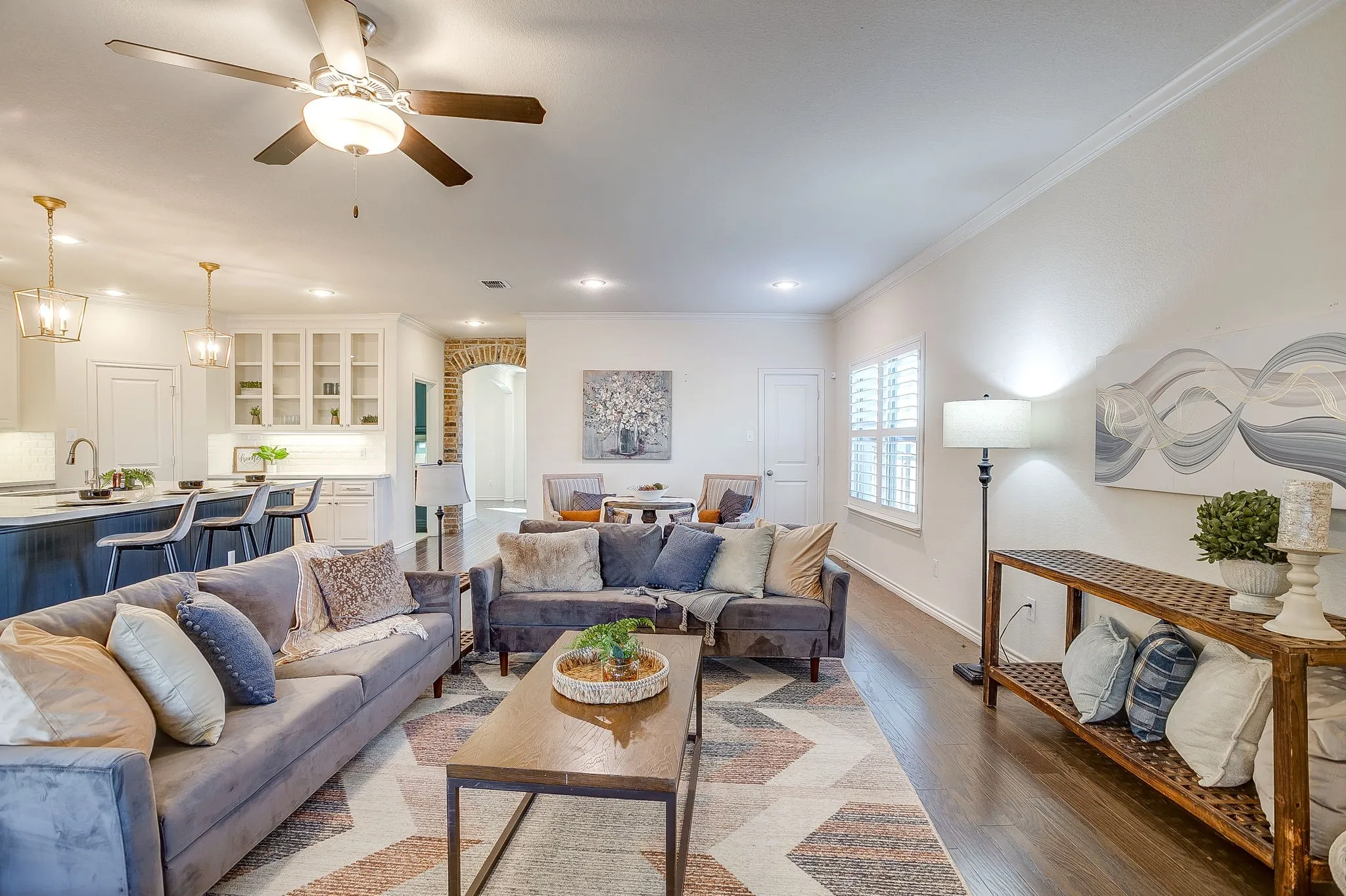 Living area with wood finished floors, ornamental molding, recessed lighting, a ceiling fan, and arched walkways