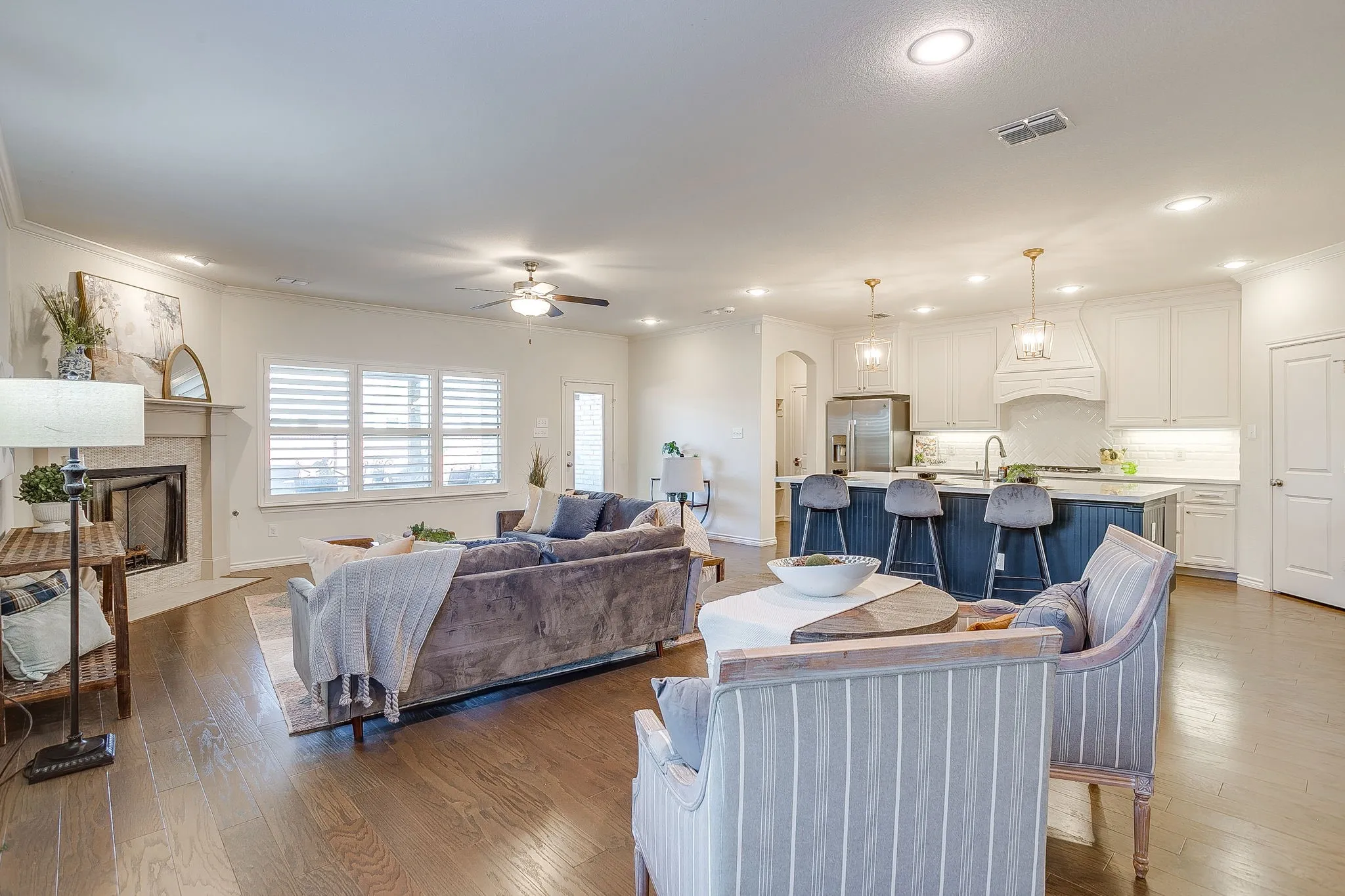 Living room with wood-type flooring, a ceiling fan, ornamental molding, recessed lighting, and a premium fireplace