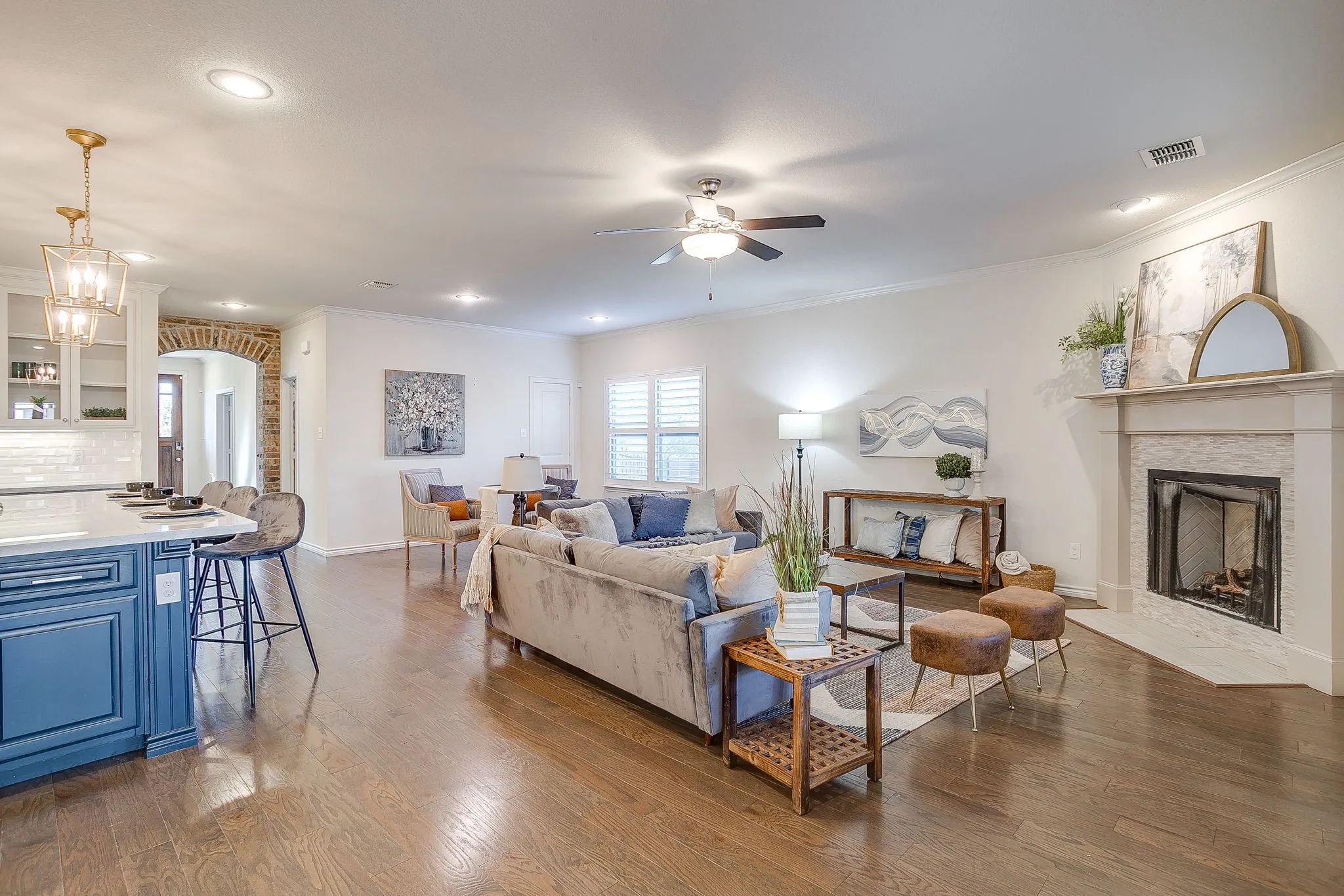 Living room with crown molding, light wood-style flooring, a fireplace with flush hearth, a ceiling fan, and recessed lighting