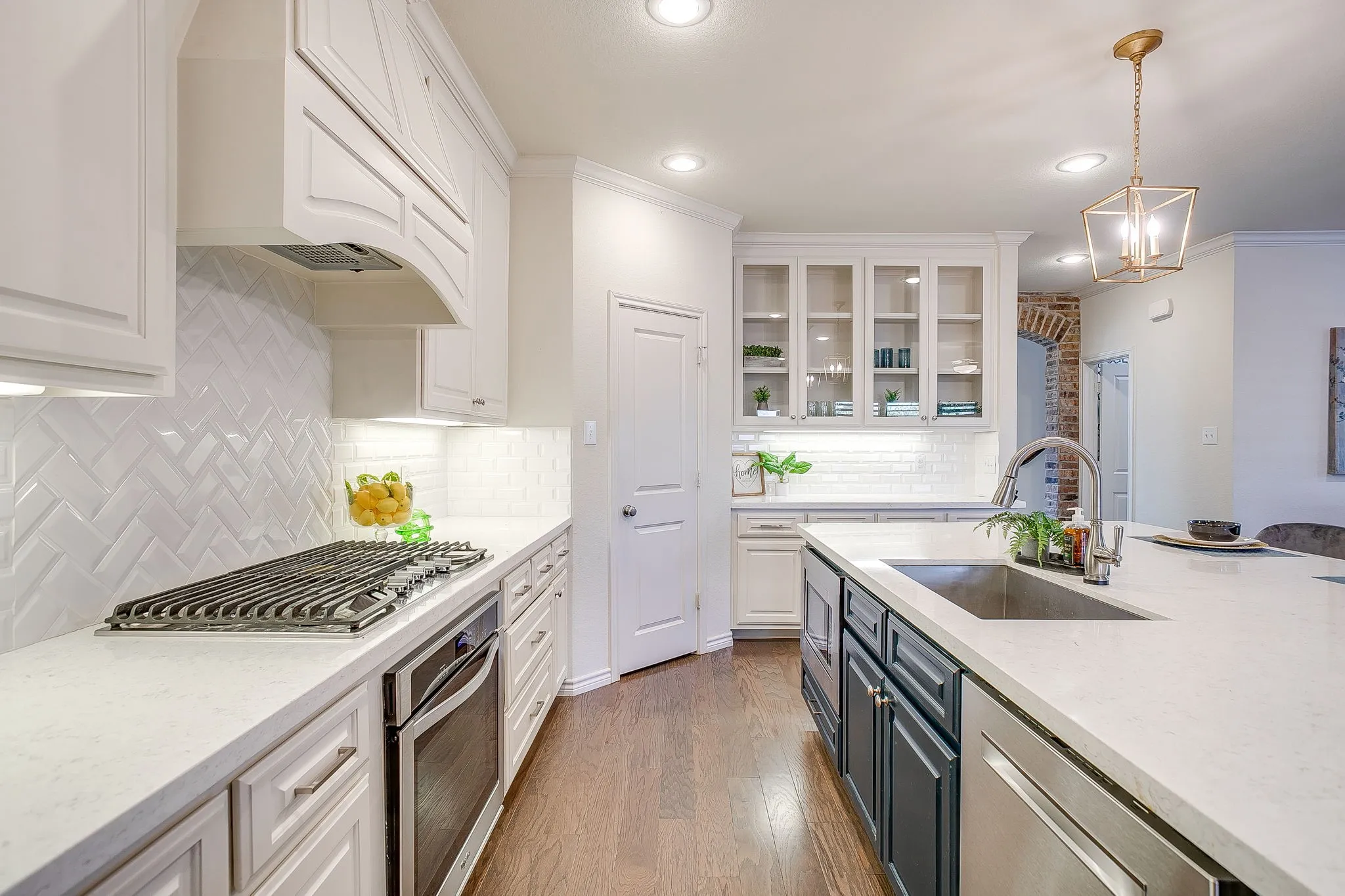 Kitchen featuring white cabinetry, light stone counters, stainless steel appliances, glass insert cabinets, and crown molding