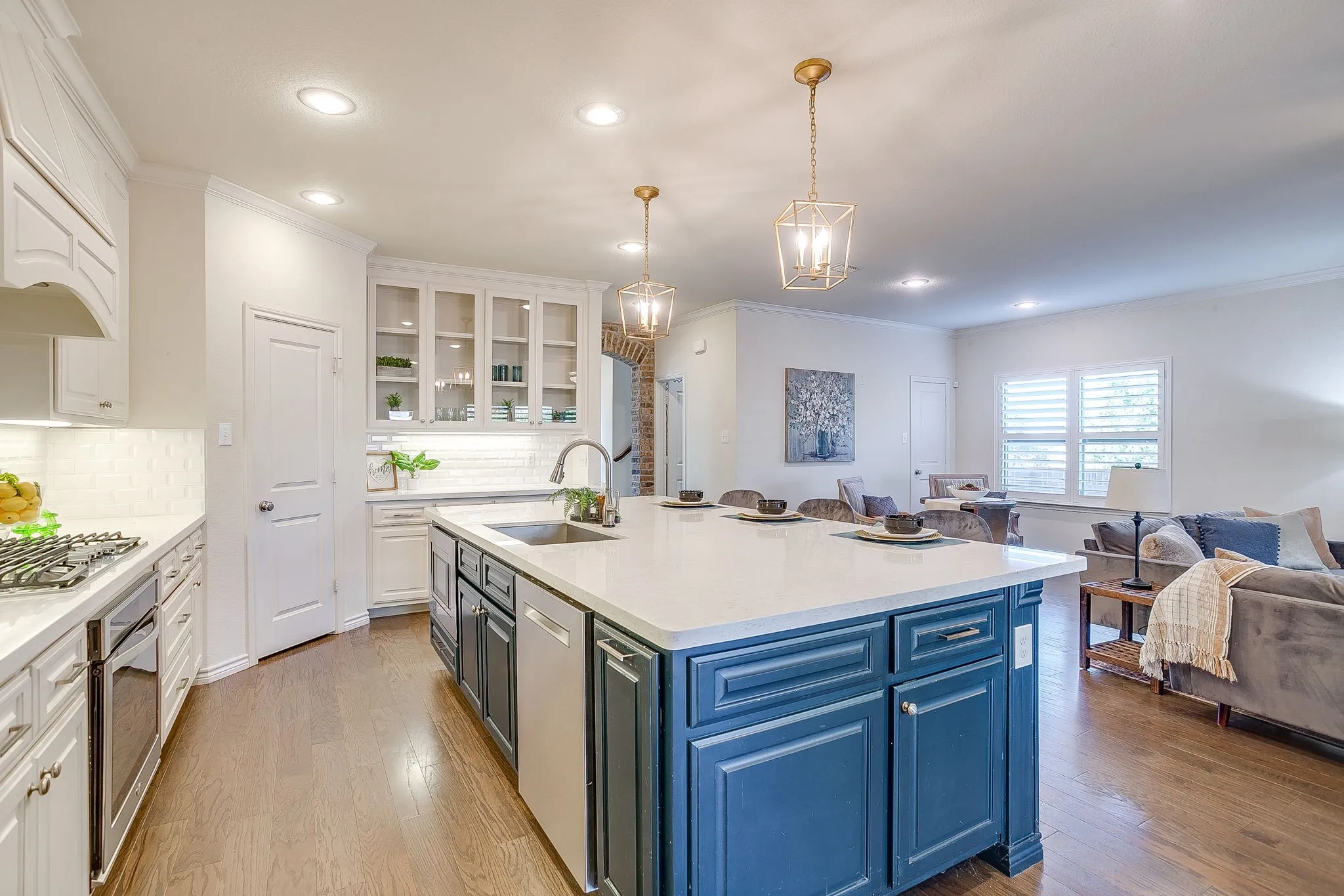 Kitchen featuring open floor plan, glass insert cabinets, white cabinetry, decorative light fixtures, and crown molding