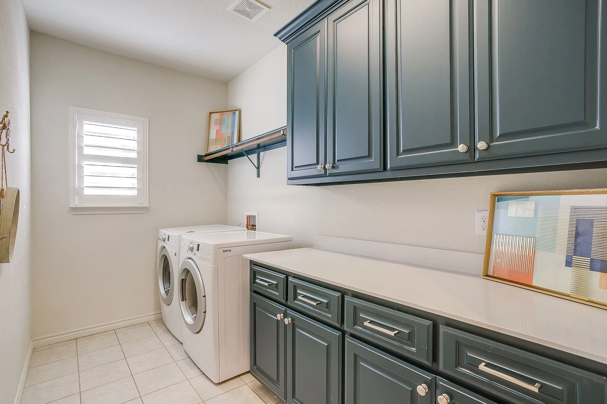 Laundry area with light tile patterned flooring, cabinet space, and washer and clothes dryer