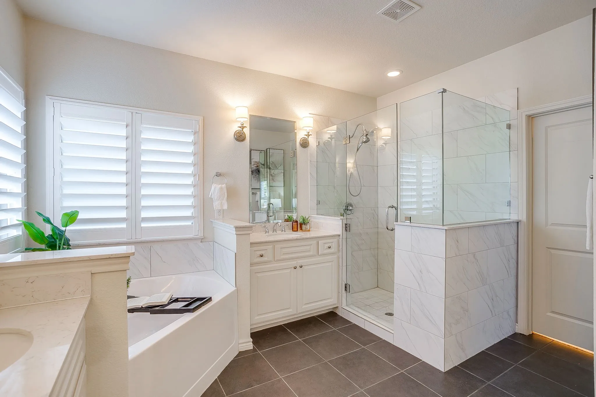 Full bath with two vanities, a bath, a shower stall, and dark tile patterned floors