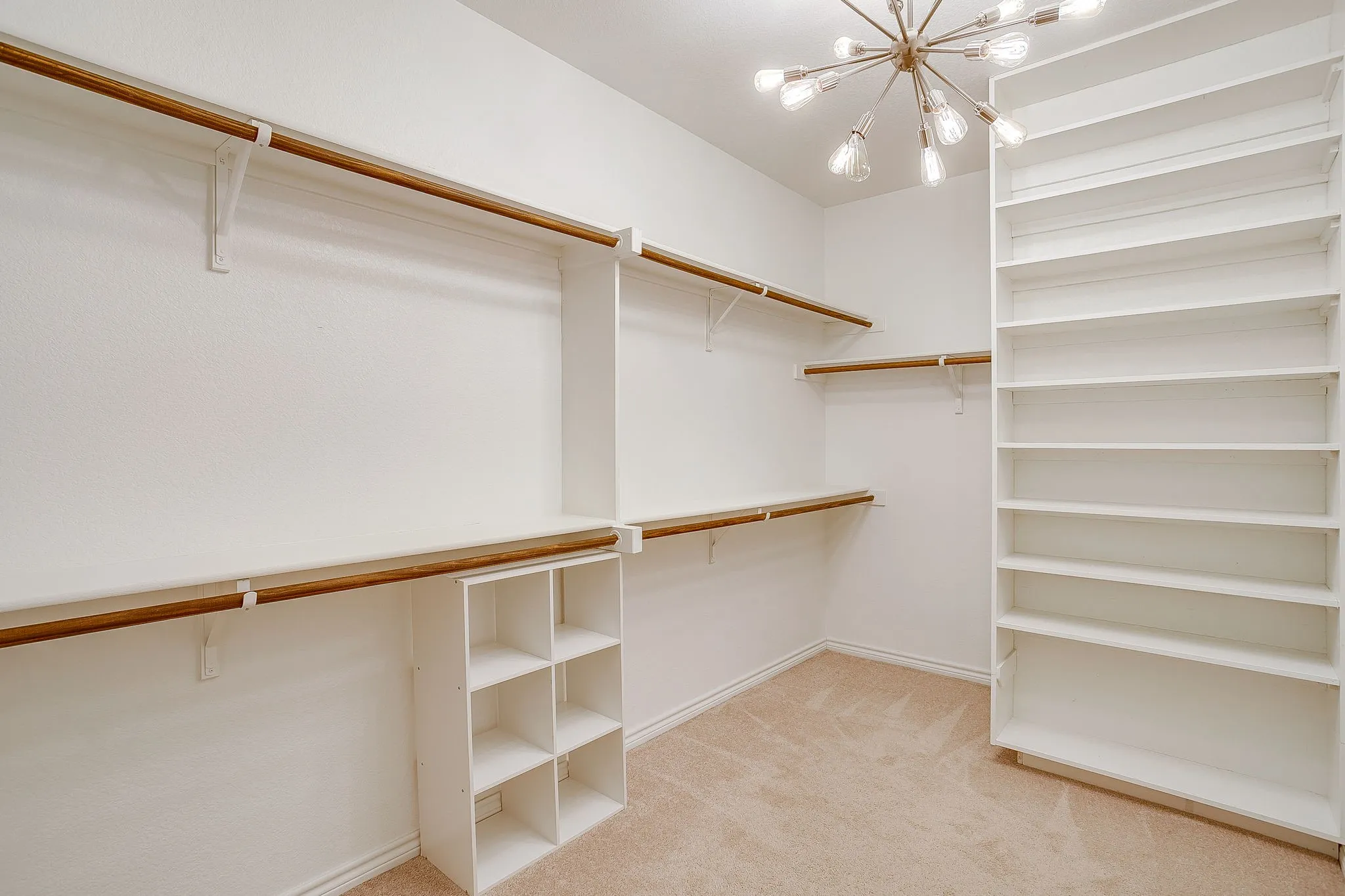 Walk in closet with light colored carpet and a chandelier