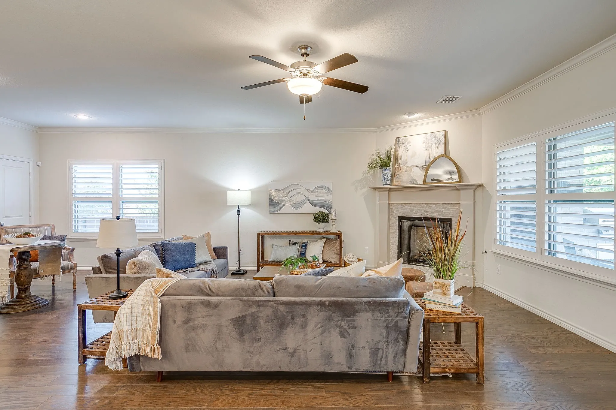 Living room featuring dark wood finished floors, a ceiling fan, ornamental molding, and a fireplace