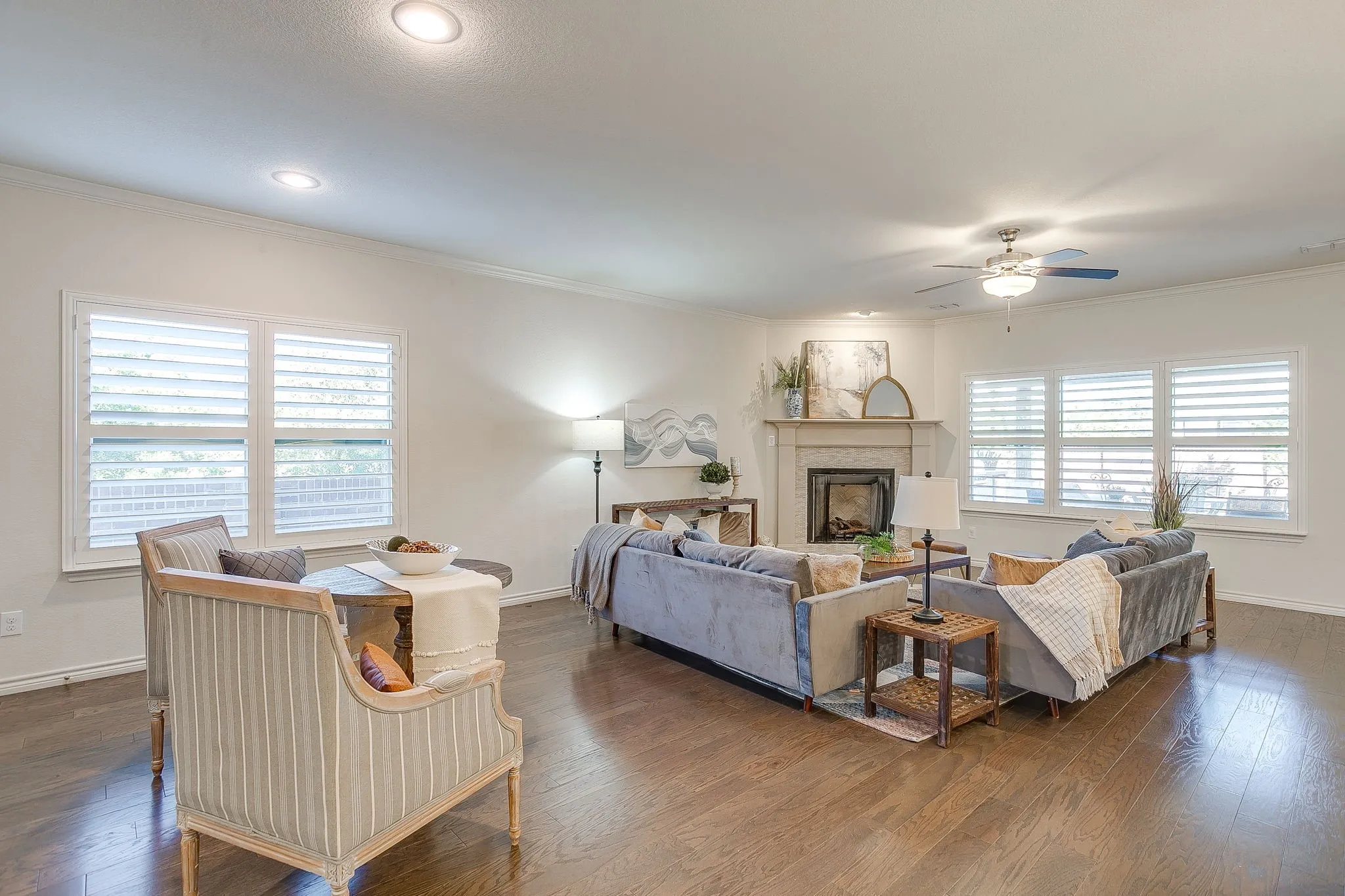 Living room with ornamental molding, dark wood finished floors, a fireplace, and a ceiling fan