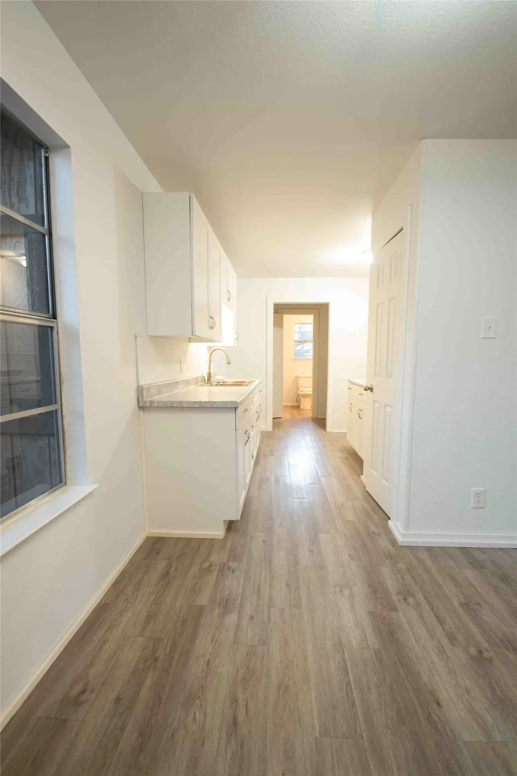 Kitchen featuring white cabinetry, light countertops, and light wood-style vinyl flooring
