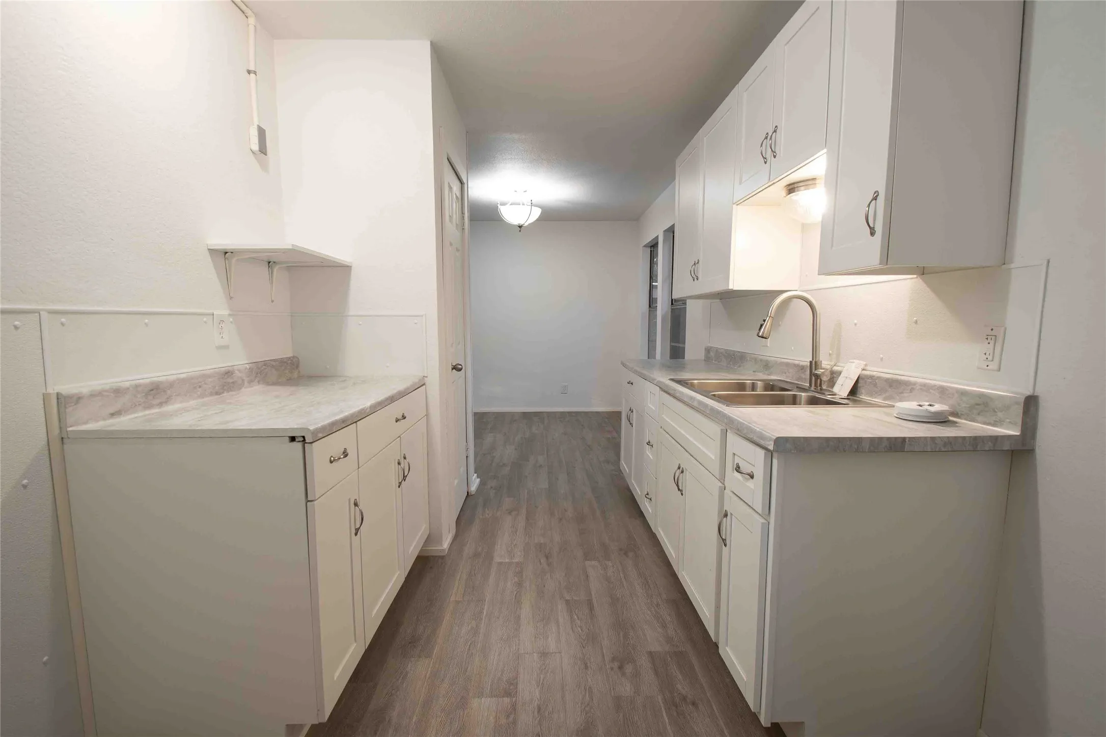 Kitchen with light countertops, white cabinetry, and dark wood-style floors