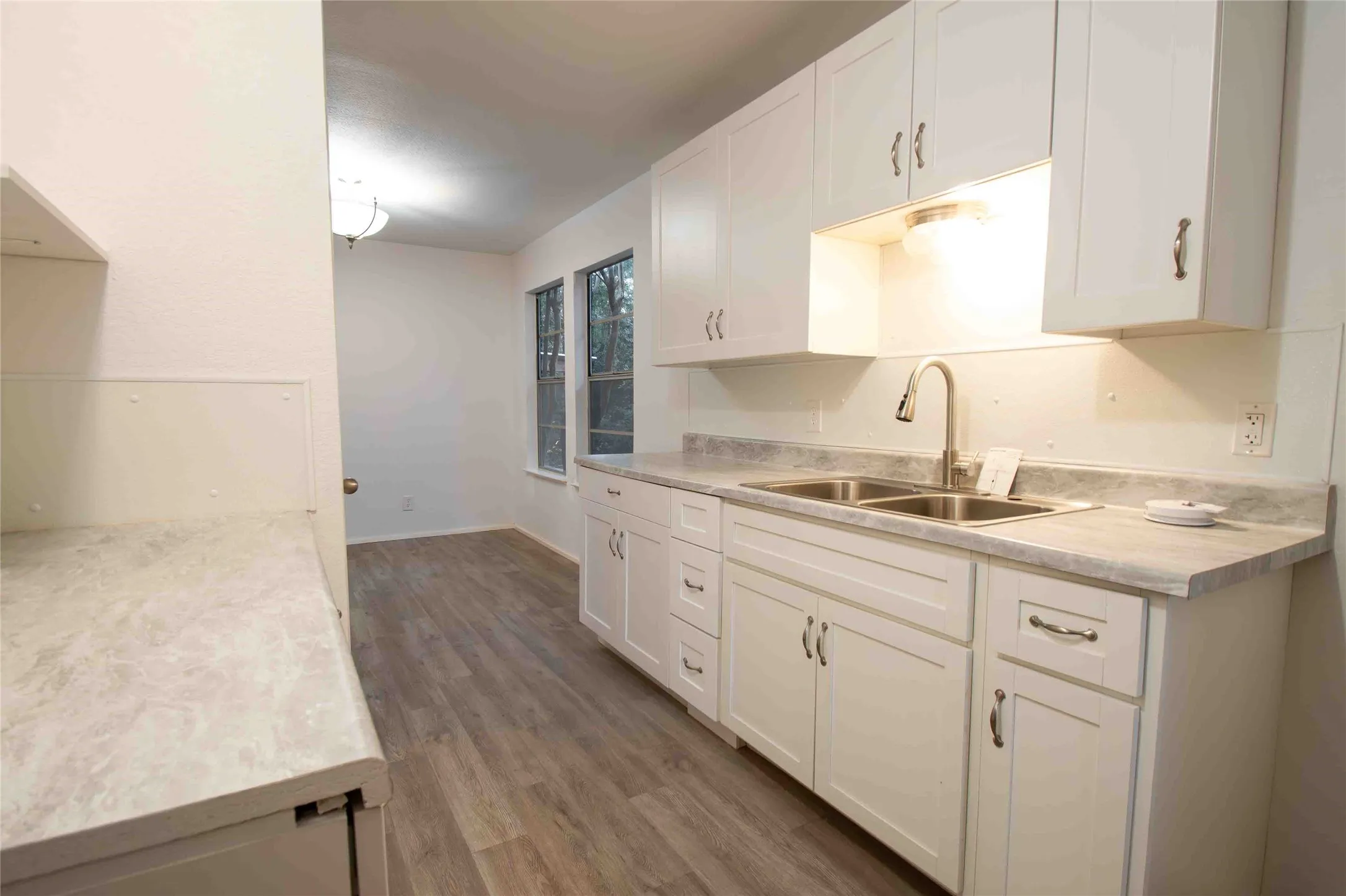 Kitchen with light countertops, white cabinetry, and dark wood-type flooring