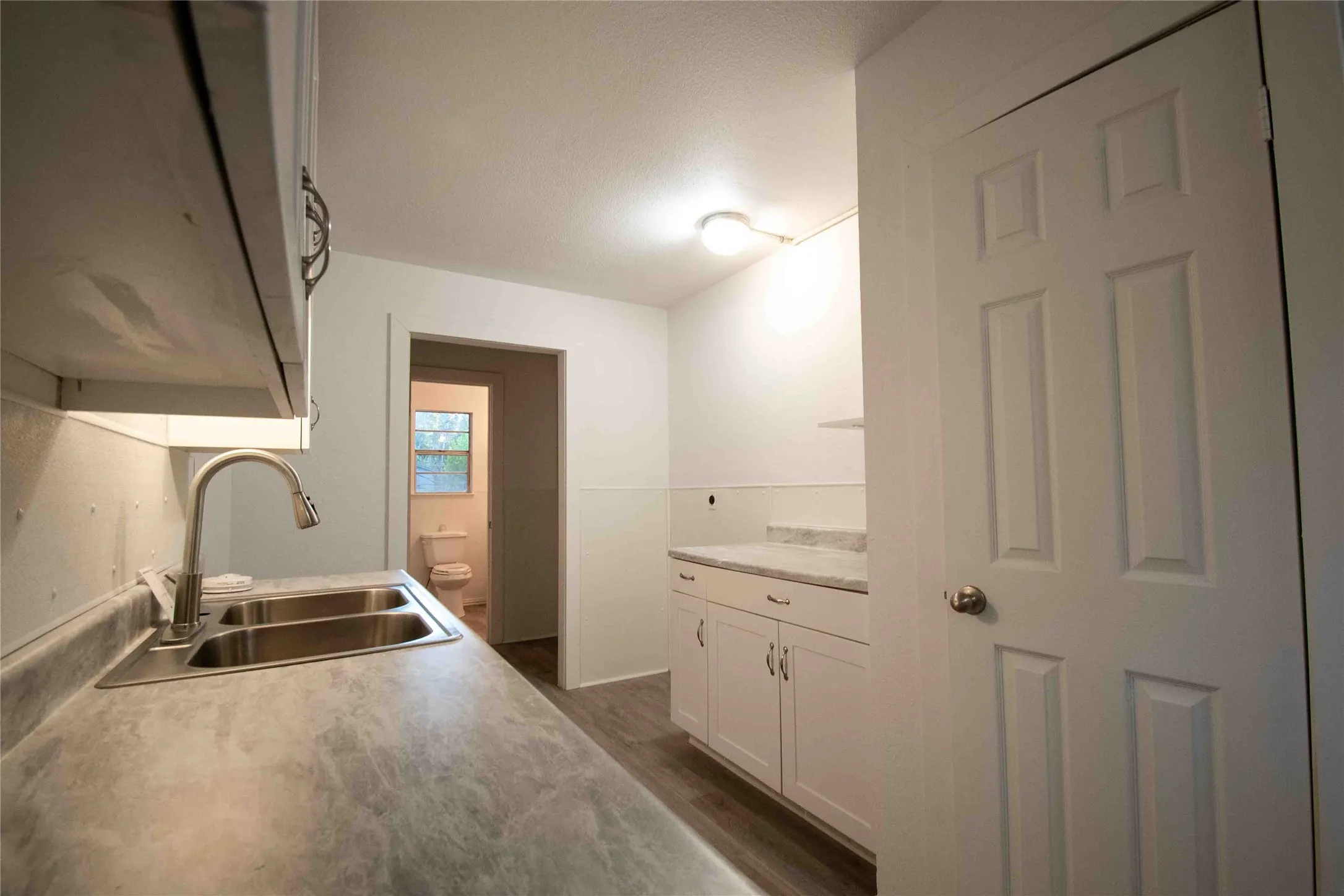 Kitchen with light countertops, dark wood-type flooring, and white cabinetry