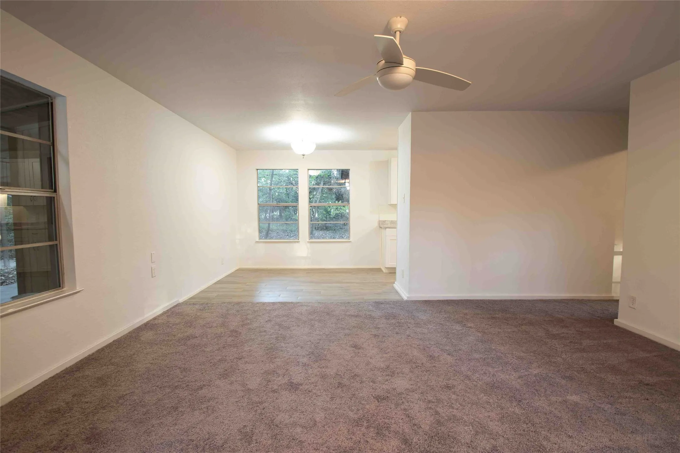 Unfurnished Living and Dining room with carpet and laminate flooring and a ceiling fan