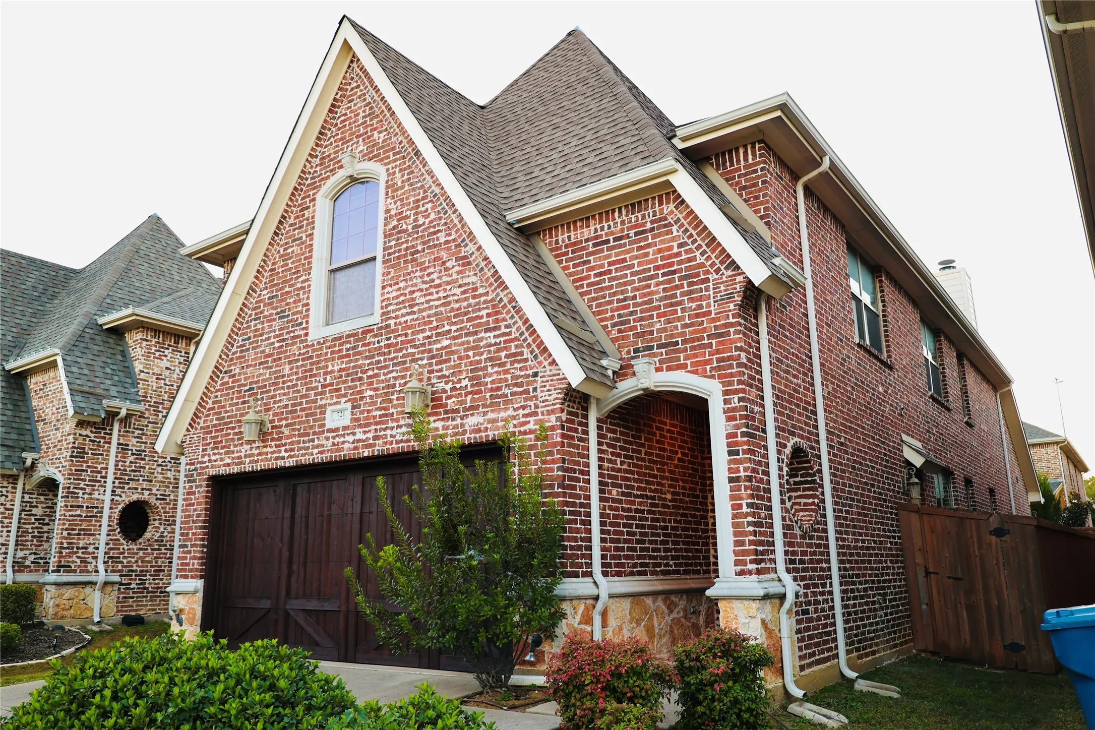 View of front facade featuring brick siding, roof with shingles, and a garage