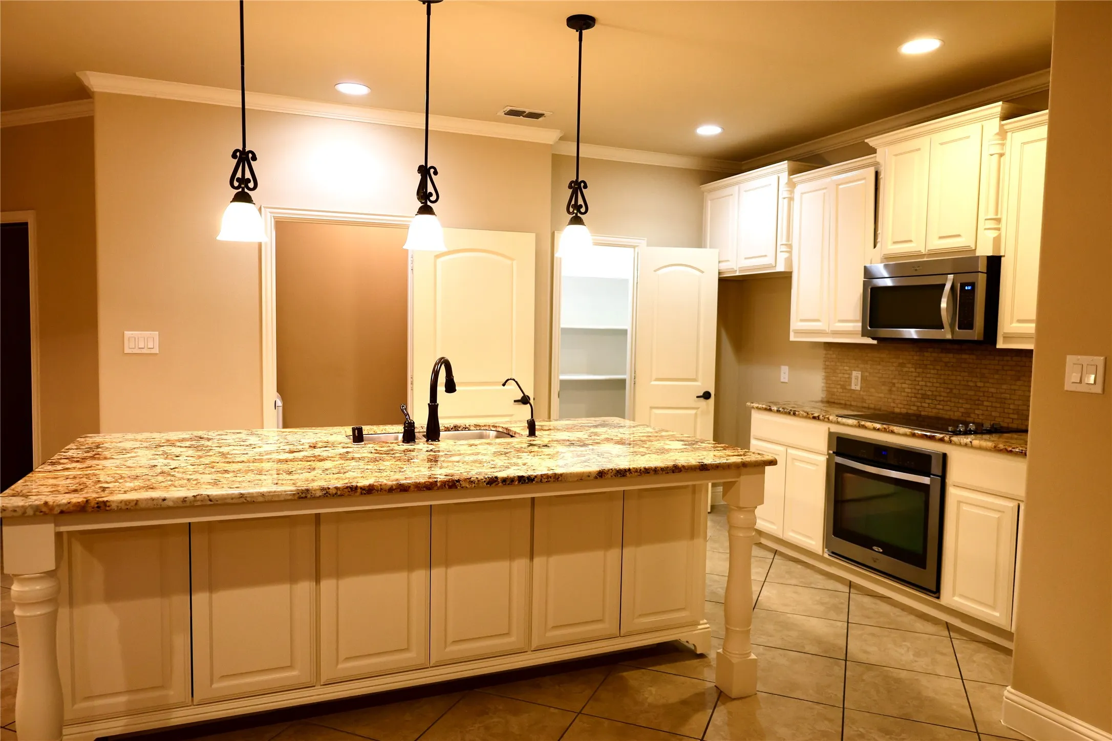 Kitchen with ornamental molding, light stone counters, light tile patterned floors, backsplash, and appliances with stainless steel finishes