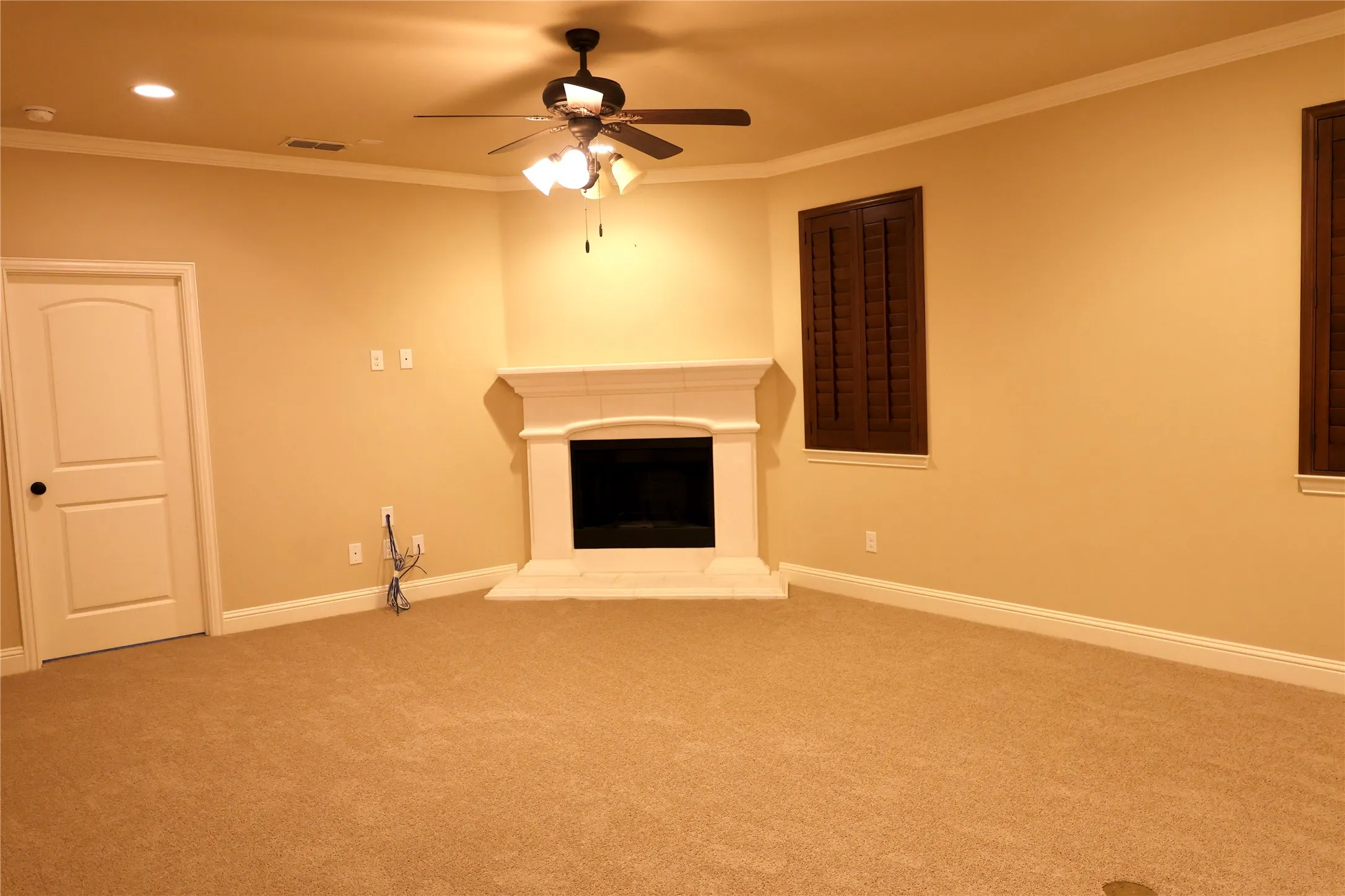 living room featuring a fireplace with raised hearth, ornamental molding, carpet, recessed lighting, and a ceiling fan