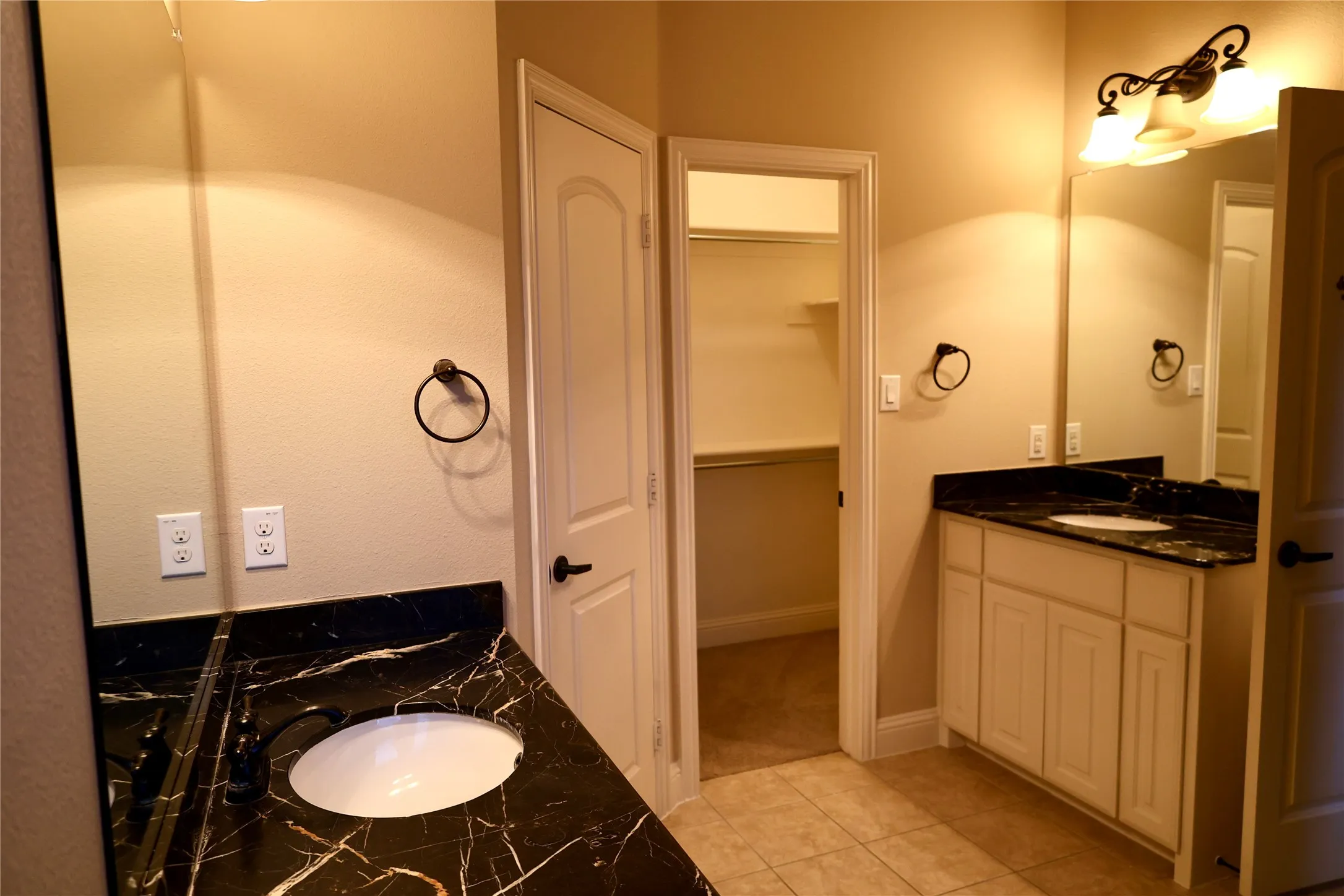 Full bath featuring two vanities, light tile patterned floors, and a spacious closet