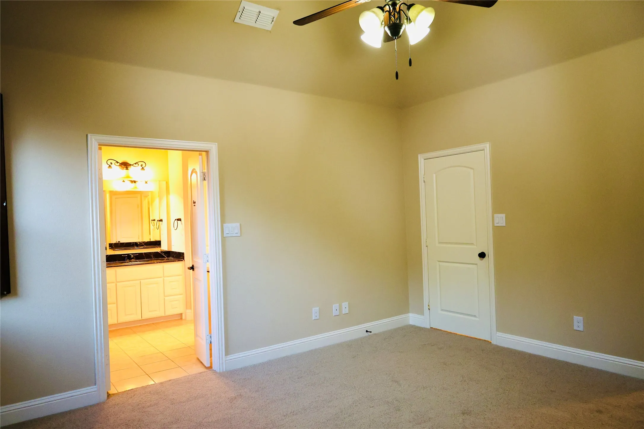 bedroom featuring light carpet, ceiling fan, light tile patterned flooring, and ensuite bath