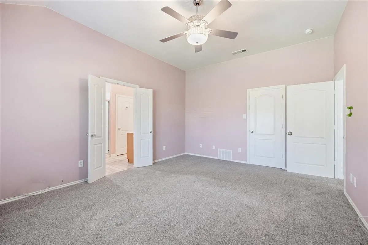 Unfurnished bedroom featuring light carpet and a ceiling fan