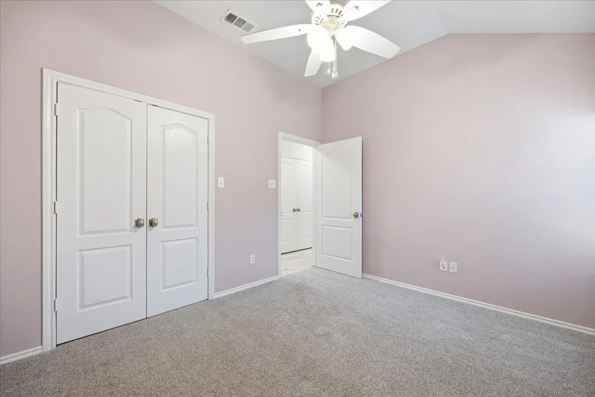 Unfurnished bedroom with carpet floors, a closet, ceiling fan, and lofted ceiling