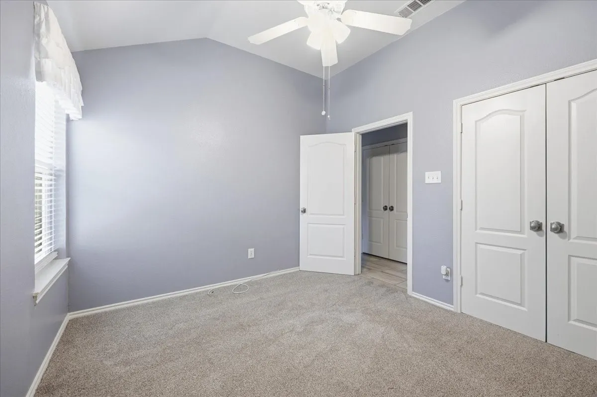 Unfurnished bedroom with lofted ceiling, carpet floors, a closet, and ceiling fan