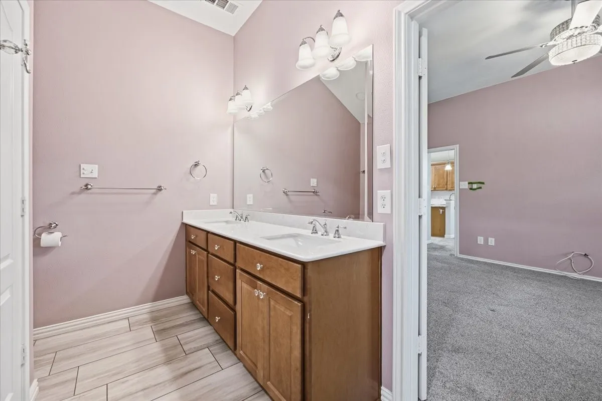 Full bath with double vanity, wood finish floors, and a ceiling fan