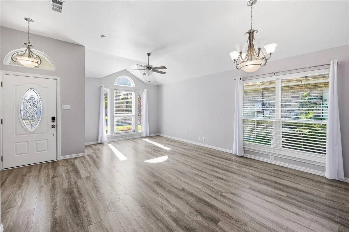 Entryway featuring light wood-style flooring, vaulted ceiling, a chandelier, and ceiling fan