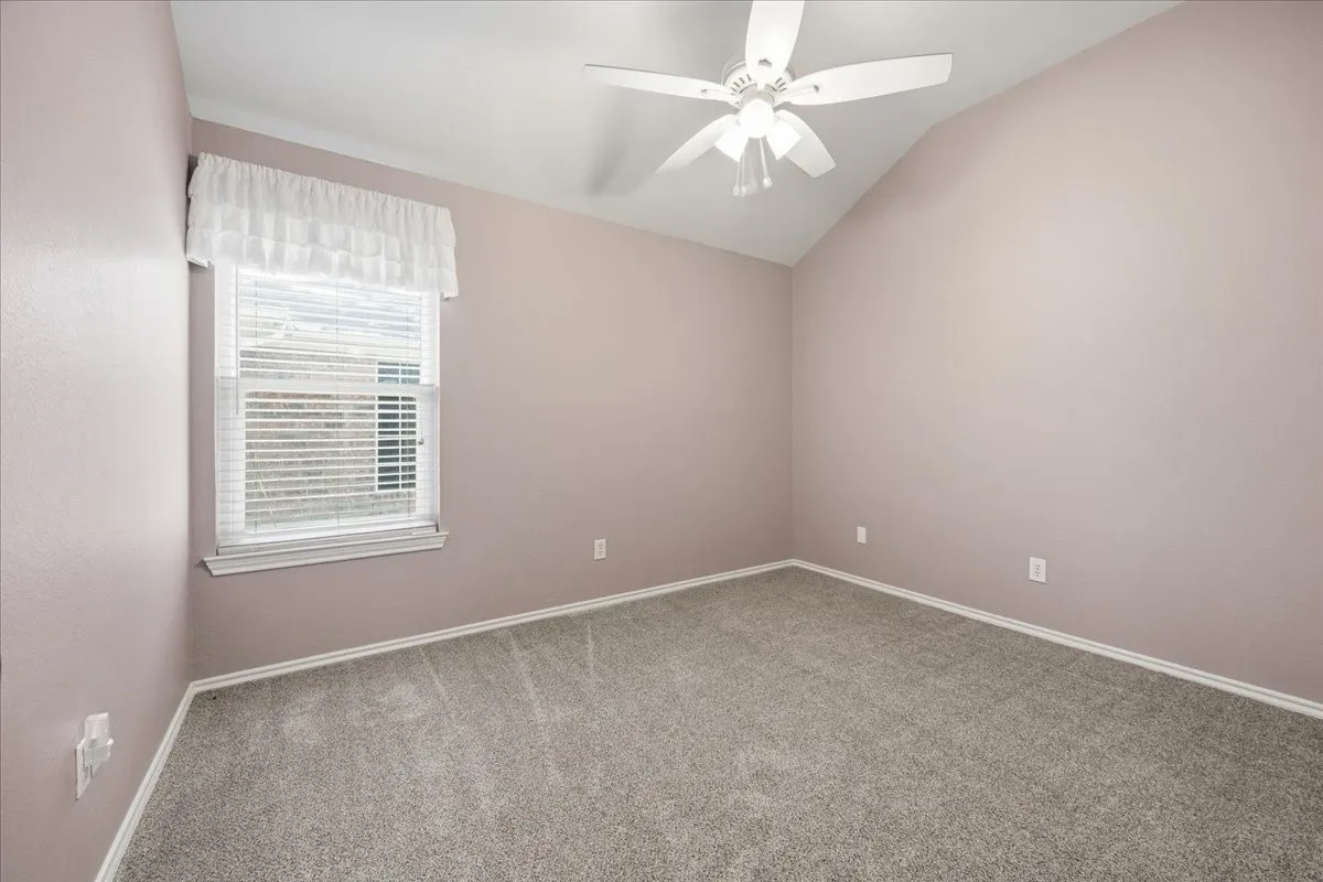 Carpeted spare room with vaulted ceiling and ceiling fan