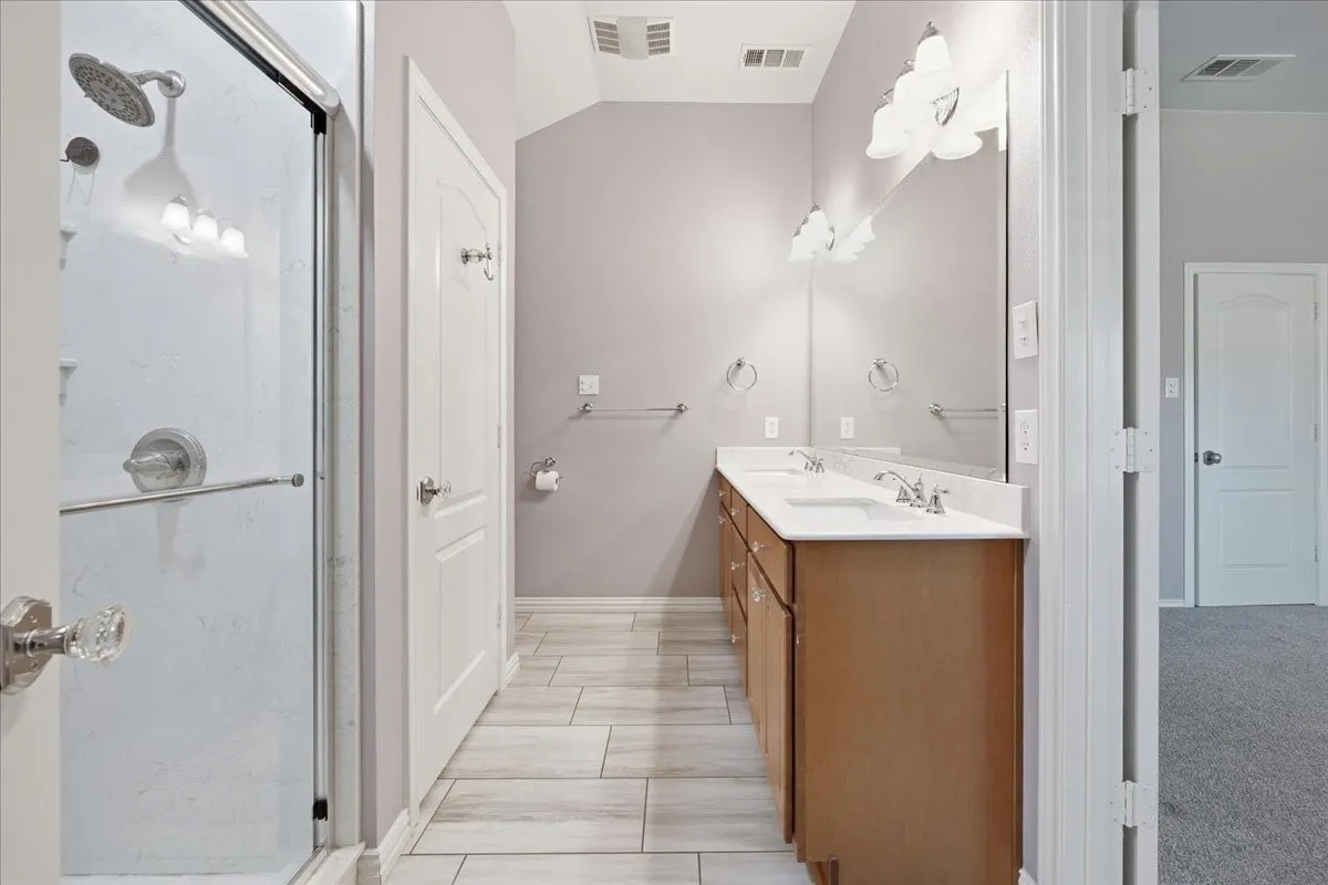 Full bathroom featuring double vanity and a stall shower