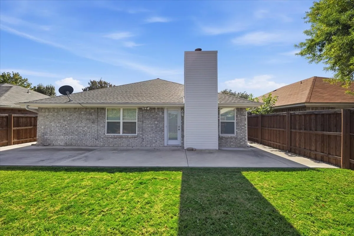 Rear view of property with a fenced backyard, brick siding, a chimney, and a patio