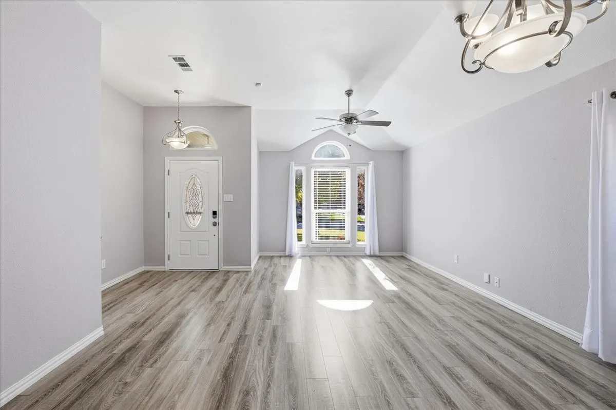 Foyer entrance featuring light wood-style flooring, vaulted ceiling, a chandelier, and ceiling fan