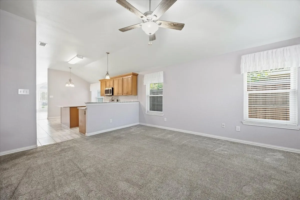 Unfurnished living room with lofted ceiling, healthy amount of natural light, and light colored carpet