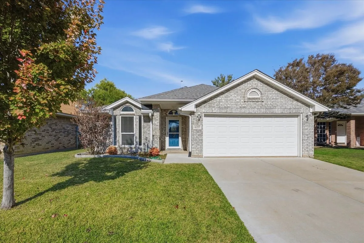 Ranch-style house featuring a front lawn, brick siding, and driveway