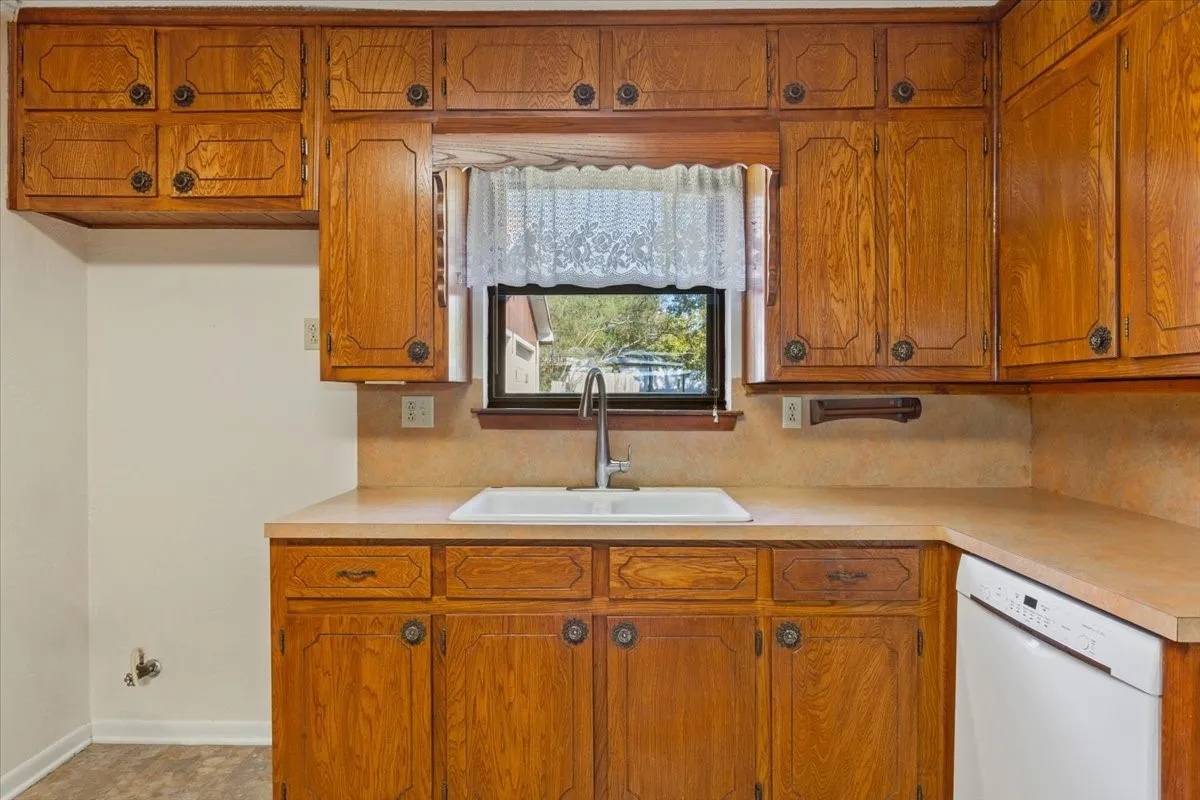 Kitchen featuring brown cabinetry, dishwasher, and light countertops