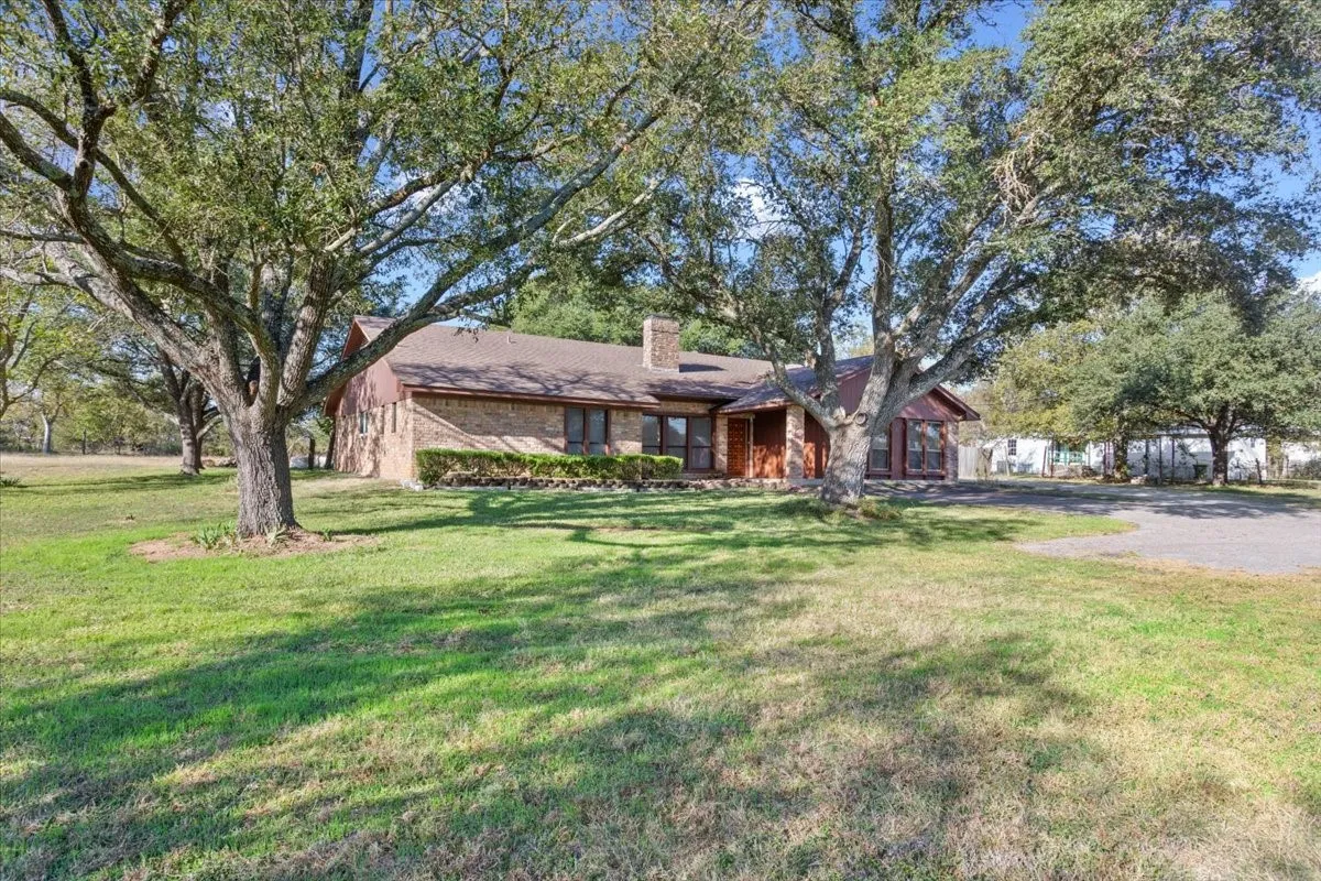 Ranch-style home with a front yard, a chimney, and brick siding