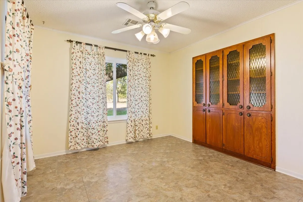 Unfurnished room with crown molding, a textured ceiling, and ceiling fan