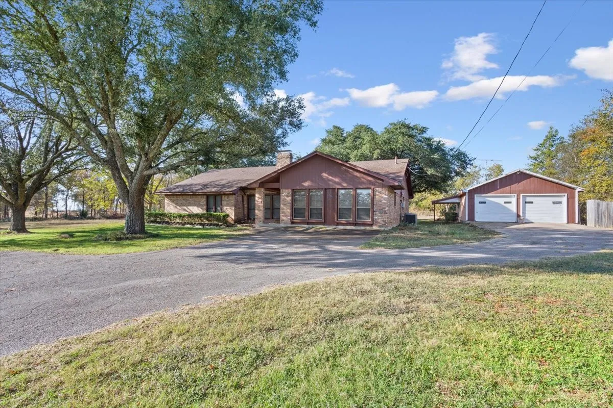 Single story home featuring an outbuilding, a detached garage, a chimney, and a front yard