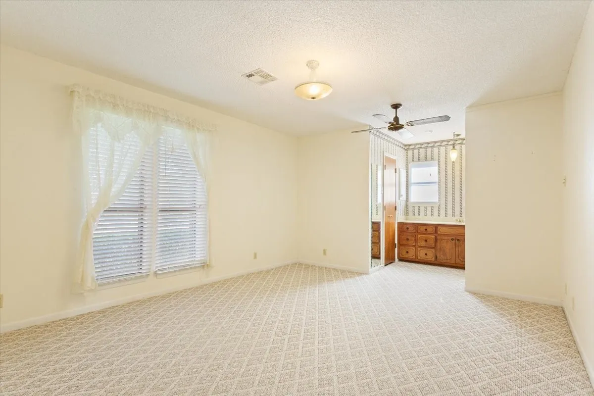 Carpeted spare room featuring a textured ceiling and a ceiling fan